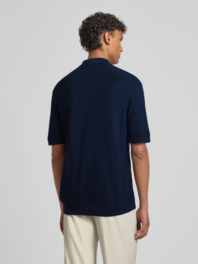 Męski model nosi Regular Fit Poloshirt aus reiner Bio-Baumwolle Modell 'CRAN' von SELECTED HOMME, granatowy, faktura dzianiny, krój regular fit, krótki rękaw, ściągacze, widok całej sylwetki z tyłu.