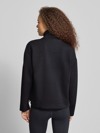 Frauenmodel trägt schwarzes Relaxed Fit Sweatshirt mit Reißverschluss von adidas Sportswear, elastischer Material-Mix, Rollkragen, Ganzkörperansicht Rückansicht.