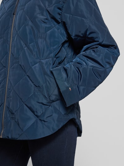 Kobieta nosi Regular Fit Bomberjacke mit College-Kragen od Tommy Hilfiger, granatowy kolor, logo, materiał wodoodporny, boczne kieszenie, detal zbliżenia na górną część ciała