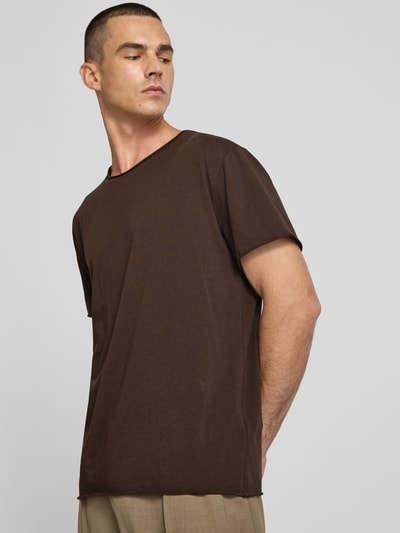 Männermodel trägt T-Shirt mit Rundhalsausschnitt von Filippa K in Braun, reine Baumwolle, Regular Fit, Rollsaum, Kurzarm, Ganzkörperansicht von vorne.
