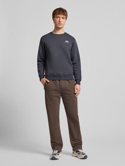 Männermodel trägt Sweatshirt mit gerippten Abschlüssen von Alpha Industries, Baumwoll-Mix, lockerer Schnitt, Rundhalsausschnitt, Label-Details, Ganzkörperansicht von vorne.
