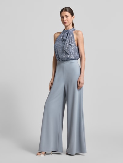 Vrouwenmodel draagt Regular Fit Jumpsuit met paillettenbesatz van Swing in lichtblauw, elastische materiaalmix, sierstrik, opstaande kraag, mouwloos design, getailleerd met rugdecolleté, ganzebodyvooraanzicht.
