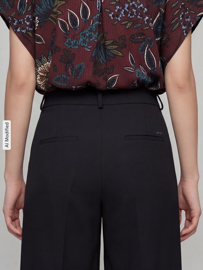 Frauenmodel trägt Weite Hose aus Viskose-Mix Modell 'MELLI S' von Brax in Schwarz, glatte Textur, Ganzkörperansicht Rückansicht, Damen Weite Hose von Brax.