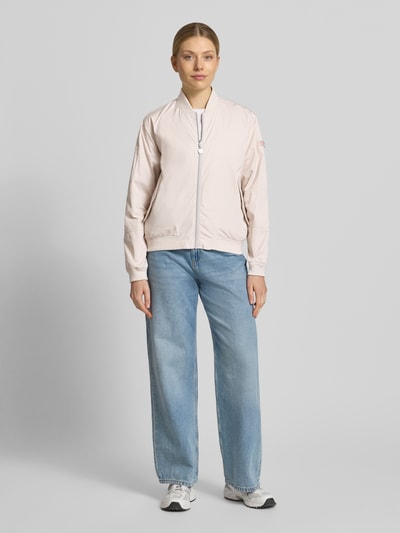 Frauenmodel trägt Regular Fit Bomberjacke mit Stehkragen Modell 'Brooklyn' von Frieda & Freddies in zartem Rosa und Jeans, Eingrifftaschen, Reißverschluss, elastische Abschlüsse, Rückenlänge bei Größe 36: 59 cm, Schulterbreite: 44 cm, Brustweite: 52 cm, Ärmellänge: 51 cm, Ganzkörperansicht von vorne