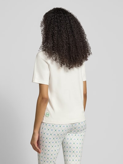 Frauenmodel trägt Regular Fit T-Shirt mit Ziersteinbesatz von Marc Cain in Weiß aus reiner Baumwolle, Motiv-Print, Rückenlänge 56 cm, Ganzkörperansicht Rückansicht.
