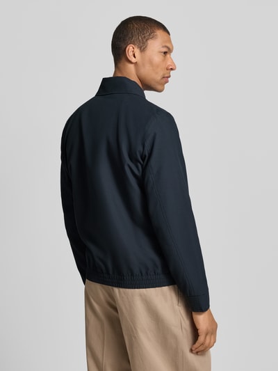 Męski model nosi Regular Fit Blouson mit Umlegekragen Modell 'LIGHT 2.0' od Strellson, gładki granatowy materiał, krój regular fit, kołnierz wykładany, zamek błyskawiczny, długie rękawy z ściągaczem, dolny brzeg elastyczny, kieszeń napoleonka i boczne kieszenie wpuszczane, widok całej sylwetki z tyłu.
