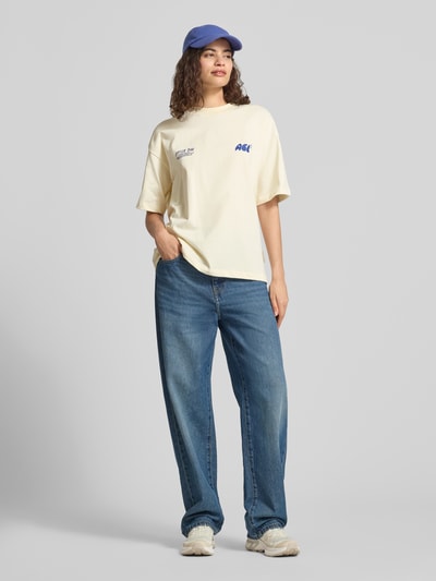 Modelka prezentuje oversized t-shirt z nadrukiem z logo, damski t-shirt z bawełny, okrągły dekolt, długość tyłu 64 cm w rozmiarze S, Oversized T-Shirt mit Label-Prints od ANOTHER COTTON LAB, jasne kolory, gładka faktura, pełny widok z przodu