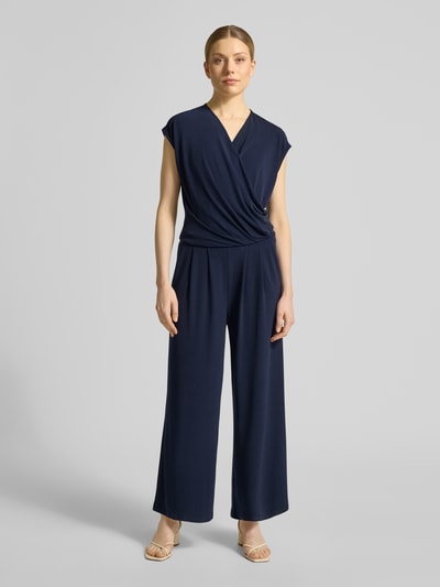 Vrouwenmodel draagt Jumpsuit in Wickel-Optik met V-Ausschnitt van ROBE LÉGÈRE in donkerblauw materiaalmix met stretch, regular fit, wikkellook, V-hals; ruglengte maat 36: 49 cm, borstwijdte: 42 cm, totale lengte: 147 cm, binnenbeenlengte: 63 cm; full body vooraanzicht.