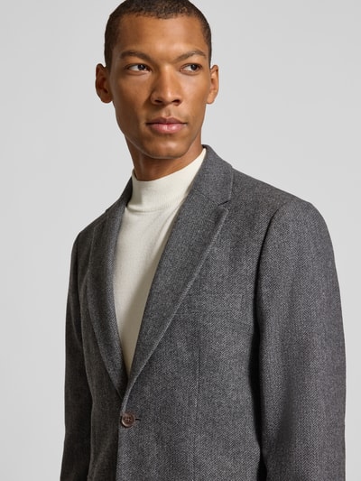 Männermodel trägt Slim Fit Sakko mit Pattentaschen aus Wolle von Selected, graue Webware mit Reverskragen, Nahaufnahme Oberkörper.