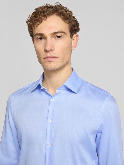 Männermodel trägt Slim Fit Business-Hemd mit Kentkragen von Jake*s in Hellblau, reine Baumwolle, glatte Textur, Nahaufnahme Oberkörper.