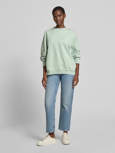 Frauenmodel trägt Oversized Sweatshirt mit Logo-Stitching von Anine Bing aus reiner Baumwolle im Oversized-Fit, Rundhalsausschnitt, elastische Abschlüsse, hellgrün, Rückenlänge bei Größe S 63 cm, Ganzkörperansicht von vorne.