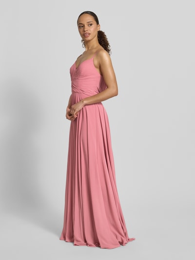 Frauenmodel trägt Abendkleid mit Drapierungen und V-Ausschnitt von Mascara, Taillierter Schnitt, Maxikleid, rosa Stoff, Ganzkörperansicht von vorne. Rückenlänge bei Größe 36: 128 cm, Brustweite bei Größe 36: 32 cm.