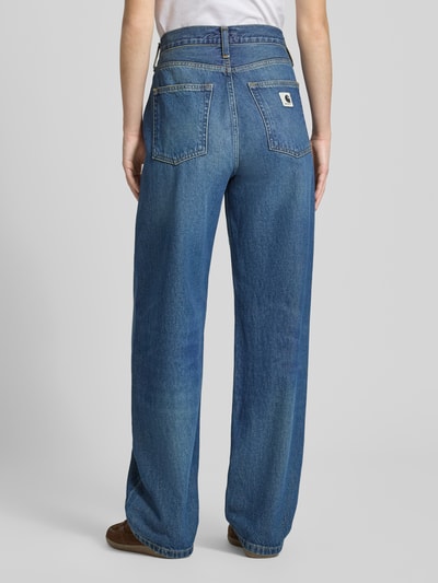 Frauenmodel trägt Tapered Fit Jeans im 5-Pocket-Design von Carhartt Work In Progress aus reiner Bio-Baumwolle, blaue Washed-Optik, Bundweite bei Größe 27: 38 cm, Innenbeinlänge 78 cm, Ganzkörperansicht Rückansicht.