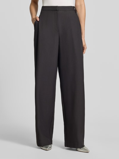 Frauenmodel trägt Regular Fit Barrel Leg Hose mit Viskose-Anteil Modell 'Hentessa-1' von HUGO in Schwarz mit Twill-Struktur, Nahaufnahme Unterkörper, unifarbene Optik, High Waist, Kettchen-Detail, seitliche Eingrifftaschen.