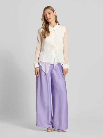 Vrouwenmodel draagt Regular Fit Bluse mit Knotendetail Modell 'Miley' van GUIDO MARIA KRETSCHMER WOMAN, wit met knoopsluiting, hemdkraag, lichte transparantie, combinatie met lila broek, textuurmix, volledig zicht van voren.
