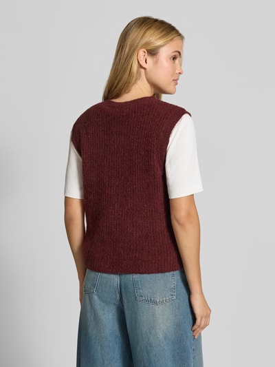 Frauenmodel trägt Regular Fit Weste mit Alpaka-Woll-Anteil von American Vintage, elastyczna mieszanka materiałów, imitacja dzianiny, detal z logo, listwa guzikowa, długość tyłu w rozmiarze S: 53 cm, widok całej sylwetki od tyłu