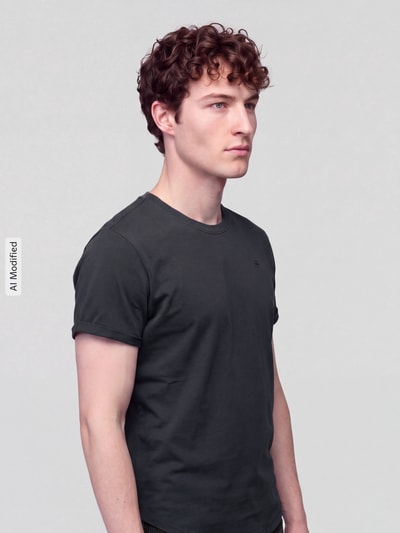 Männermodel trägt Relaxed Fit T-Shirt aus reiner Baumwolle Modell 'Lash washed' von G-Star RAW in Dunkelgrau, Ganzkörperansicht von vorne, KI-modifiziertes Bild.