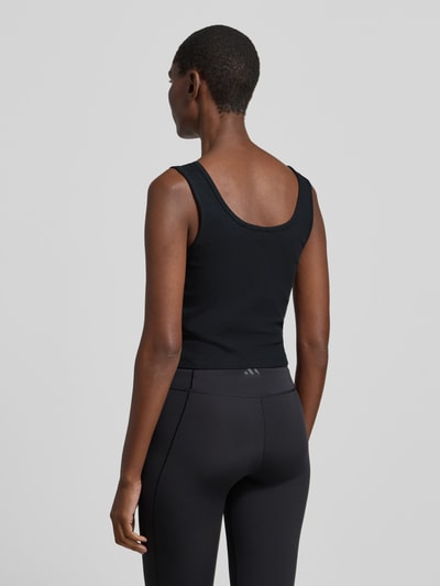 Frauenmodel trägt Slim Fit Top mit Logo-Stitching Modell 'Circe' von Guess Activewear, schwarz, elastischer Material-Mix, Rückansicht Ganzkörperansicht.