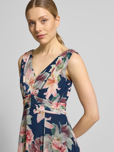 Frauenmodel trägt Maxikleid mit V-Ausschnitt und Gehschlitz von Christian Berg Cocktail im Allover-Look, Material-Mix mit Stretch-Anteil, Nahaufnahme Oberkörper.