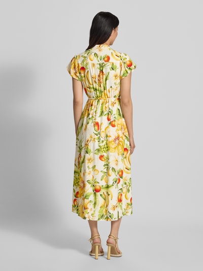 Frauenmodel trägt Abendkleid aus Leinen-Viskose-Mix Modell 'Posie' von Forever New mit gelb-grünem Muster und Taillenband, Ganzkörperansicht Rückansicht. Taillierte Passform, Stehkragen mit V-Ausschnitt, Kurzarm, Kontext: Rückenlänge Größe 36 ca. 38 cm, Brustweite 38 cm, Ärmellänge 16 cm.