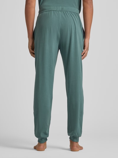 Männermodel draagt Comfort Fit Sweathose aus Baumwoll-Mix Modell 'MIX&MATCH PANTS' van BOSS in effen groen jersey, elastische tailleband en boorden, zijzakken, label stitching, ganzkörperansicht rückansicht.