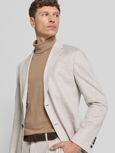 Männermodel trägt Sakko mit floraler Applikation Modell 'Hoverest' von JOOP! Collection, krój regular fit, mieszanka wiskozy, kolor jasny beż, marynarka z klapami, zapięcie na guziki, kieszeń na piersi, boczne kieszenie, długość tyłu w rozmiarze 50: 73 cm, szerokość w rozmiarze 50: 40 cm, długość rękawa w rozmiarze 50: 65 cm, widoczna gładka faktura, Ganzkörperansicht von vorne.