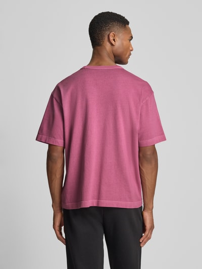 Männermodel trägt Cropped T-Shirt mit Rundhalsausschnitt von GAP in Pink, reine Baumwolle, Rückansicht, Ganzkörperansicht von hinten.
