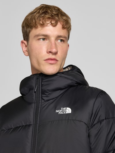 Männermodel trägt Regular Fit Jacke in Stepp-Optik von The North Face in Schwarz mit Logo-Print, Kapuze und Reißverschluss, Nahaufnahme Oberkörper.