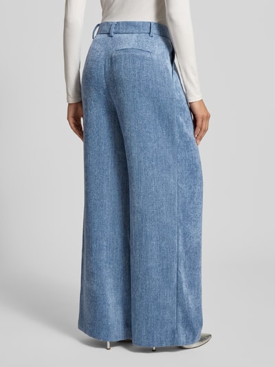 Frauenmodel trägt Wide Fit Stoffhose in Denim-Optik Modell 'Zvally' von Gestuz mit Bundfalten, Gesäßtasche, Haken- und Reißverschluss, Ganzkörperansicht Rückansicht.