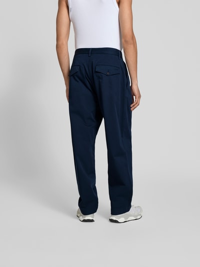 Männermodel trägt Wide Fit Stoffhose mit Bundfalten von Forét in Dunkelblau, Baumwoll-Mix, Gesäßtaschen, Rückansicht Ganzkörperaufnahme.