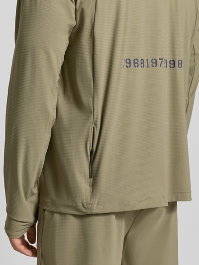 Männermodel trägt Funktionsshirt mit Stehkragen und Reißverschluss Modell 'AIR' van HALO in olijfgroen, regular fit, label-print, detailopname rug.