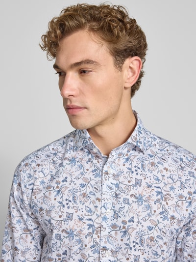 Männermodel trägt Regular Fit Businesshemd aus reiner Baumwolle von OLYMP mit floralem Muster in Blau und Beige, Nahaufnahme Oberkörper, Herren Businesshemd von OLYMP.