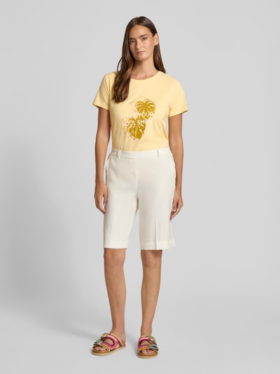 Kobiece model nosi damski t-shirt z bawełny krój regular fit, okrągły dekolt, nadruk z napisem i motywem, Soyaconcept T-Shirt mit Statement- und Motiv-Print Modell 'RINA', długość tyłu w rozmiarze S: 60 cm, jasne kolory, gładka tekstura, przód, zdjęcie całej sylwetki