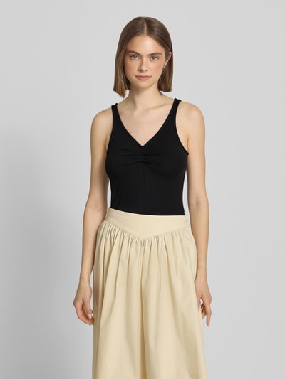 Frauenmodel trägt Slim Fit Top aus Viskose-Mix Modell 'MALIVA' von Pieces, unifarben schwarz, V-Ausschnitt, Ganzkörperansicht von vorne.