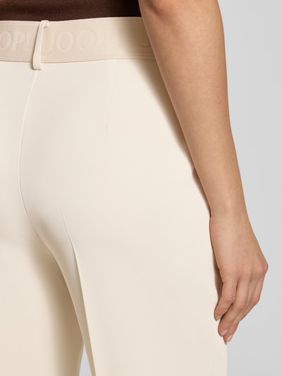 Frauenmodel trägt Hose mit elastischem Bund und Bügelfalten Modell 'Philomena' von JOOP!, cremefarben, glatte Textur, Detailaufnahme Rückenansicht.
