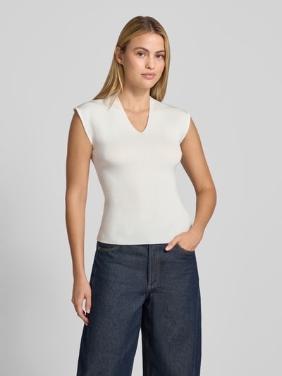 Frauenmodel trägt Stricktop mit V-Ausschnitt Modell 'CANELONS' von MANGO, taillierter Schnitt, cremeweiß, glatte Textur, Ganzkörperansicht von vorne.