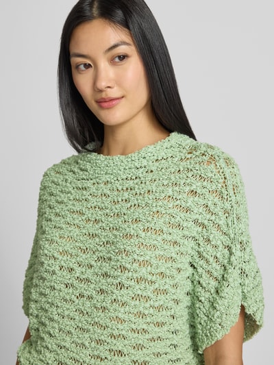 Frauenmodel trägt Relaxed Fit Pullover mit Baumwoll-Anteil von Marc Cain, semitransparent, hellgrün, strukturierte Oberfläche, Nahaufnahme Oberkörper.
