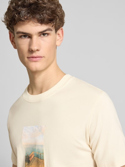 Mannenmodel draagt T-shirt met ronde hals Modell 'JORNORREBRO' van Jack & Jones in crème, rechte fit, katoen, bovenlichaam close-up.