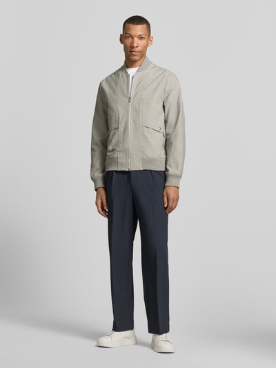Männermodel trägt Bomberjacke mit Pattentaschen und Reißverschluss von PAUL SMITH, hellgrau, Loose-Fit, Ganzkörperansicht von vorne, Herren, Stehkragen, Druckknopfverschluss, gerippte Abschlüsse, Rückenlänge 65 cm, Schulterbreite 44 cm, Brustweite 53 cm, Ärmellänge 67 cm.