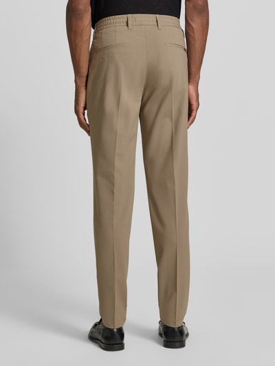 Männermodel trägt Tapered Fit Weite Hose 'MOROT JOGGER' - Marc O'Polo × DFB Travel Collection in Beige, Herren Weite Hose von Marc O'Polo, Ganzkörperansicht Rückansicht.