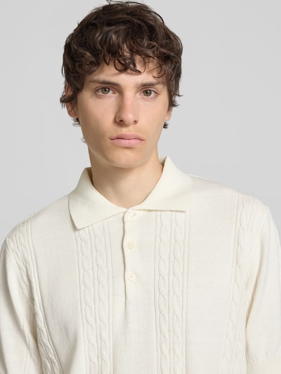 Männermodel trägt Slim Fit Strick-Poloshirt mit Zopfmuster Modell 'Miller' von Redefined Rebel aus Baumwoll-Mix, Nahaufnahme Oberkörper.