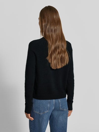 Frauenmodel trägt Strickjacke aus reinem Kaschmir von MYON in Schwarz, gerade Passform, klassische Jeans, Ganzkörperansicht Rückansicht.