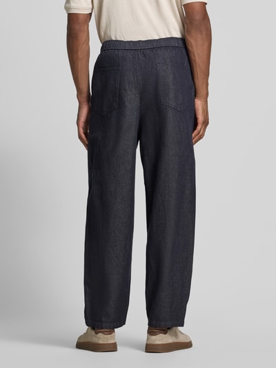 Männermodel trägt Barrel Fit Hose aus Baumwoll-Leinen-Mix Modell 'BARREL HARVEY' von Selected in dunklem Denim, Twill-Struktur, Gesäßtaschen, Ganzkörperansicht Rückansicht.