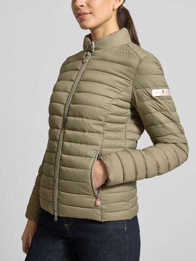 Vrouwenmodel draagt Gewatteerd jack met tweewegritssluiting Model 'JUDY' van Frieda & Freddies, slim fit, opstaande kraag, ritszakken, ruglengte 57 cm, schouderbreedte 40 cm, borstwijdte 48 cm, mouwlengte 64 cm, olijfgroen, gestikte banen, voorkant, close-up bovenlichaam.