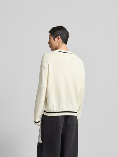 Männermodel trägt Pullover in Strick-Optik von MM6 Maison Margiela in Creme mit V-Ausschnitt, lockerer Passform, Rückenansicht