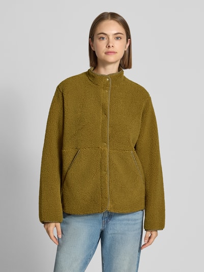 Frauenmodel trägt Teddyjacke mit Stehkragen Modell 'VERA' von JJXX in Oliv, seitliche Eingrifftaschen, Ganzkörperansicht von vorne.