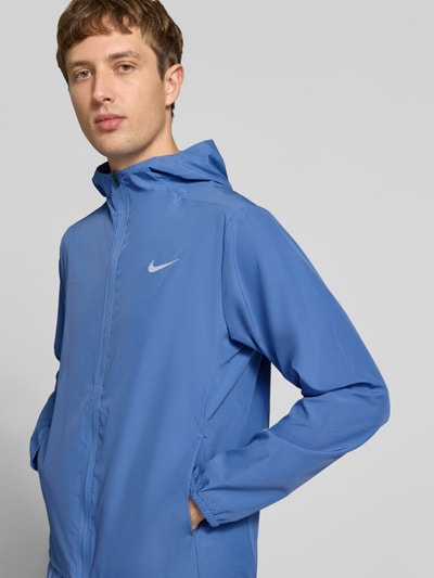 Männermodel trägt Regular Fit Trainingsjacke mit Kapuze von Nike in Blau mit glatter Textur, Nahaufnahme Oberkörper, Herren Trainingsjacke von Nike Training.