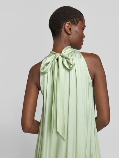 Frauenmodel trägt Relaxed Fit Abendkleid aus reiner Viskose Modell 'C_DAIRA' von BOSS Orange in mintgrün, matt glänzende Satin-Optik, unifarben, hochgeschlossen mit Neckholder, ohne Ärmel, verdeckter Reißverschluss, lang und ausgestellt, Detailaufnahme Rückansicht.