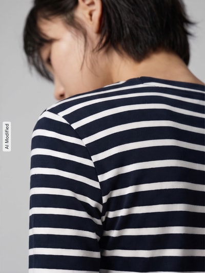Frauenmodel trägt Slim Fit Langarmshirt aus reiner Baumwolle von Tommy Hilfiger in Dunkelblau mit weißen Streifen, Nahaufnahme Rückansicht, KI-modifiziertes Bild.