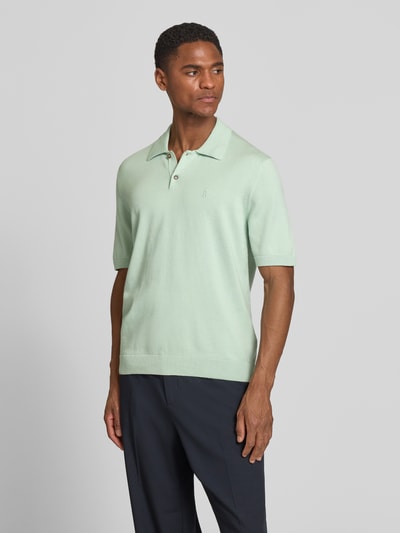 Männermodel trägt Slim Fit Poloshirt aus reiner Bio-Baumwolle von Armedangels, mintgrün, unifarben, Feinstrick, Logo-Stitching, Ganzkörperansicht von vorne.